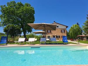 a swimming pool with chairs and an umbrella at B&B Le Scintille in San Ginesio