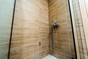 a shower in a bathroom with a wooden wall at Styliani's Cozy Apartment in Iraklitsa +20 photos