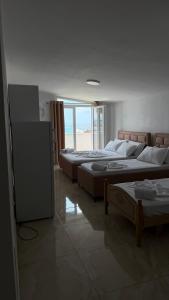 a room with three beds and a window at Hotel Progni in Shëngjin