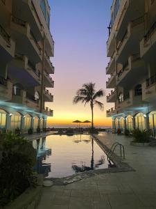 a hotel courtyard with a palm tree and a pool at Ocean Front- Marina View- Tiara Sands Resort, Sleeps 4 in Mazatlán