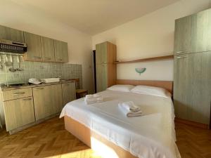 a bedroom with a white bed with towels on it at Apartmani Kordić in Barbat na Rabu