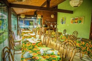 una sala da pranzo con tavoli, sedie e pareti verdi di Pousada Ocean Blue com Quadra de Beach Tenis a Rio das Ostras