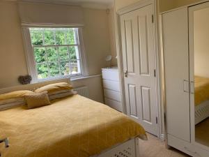 a bedroom with a bed and a window at Lovely riverside cottage, Weybridge, Surrey in Weybridge