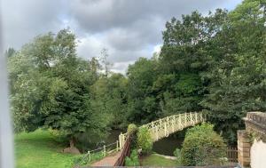 a bridge over a river with trees in the background at Lovely riverside cottage, Weybridge, Surrey in Weybridge