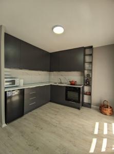 a kitchen with black cabinets and a sink and a microwave at Villa Emili in Ohrid