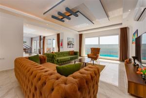 ein Wohnzimmer mit einem großen braunen Sofa und grünen Stühlen in der Unterkunft villa kayras-1 in Bezirgân