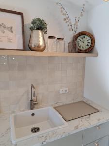 a kitchen counter with a sink and a clock on a shelf at Ferienwohnung auf dem Mühlenhof in Glinstedt +14 photos