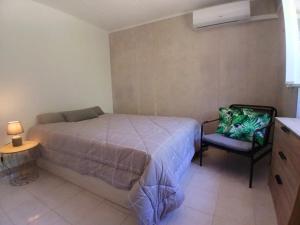 a bedroom with a bed and a chair at Casa de Férias Palmeira in Faro