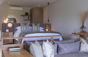 a bedroom with a bed and a couch with pillows at Lavender Farm Boutique Guest House in Franschhoek