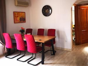 a dining room table with red chairs and a clock at Chalet Campoamor con piscina privada in Orihuela Costa