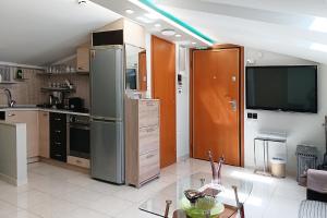 a kitchen with a stainless steel refrigerator and a tv at Metaxenia's apartment 301 in Thessaloniki