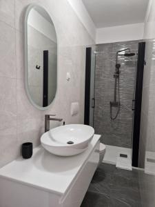 a white bathroom with a sink and a shower at Apartmani Kordić in Barbat na Rabu