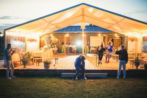 a group of people standing outside of a tent at Tūjas dīķi in Tūja