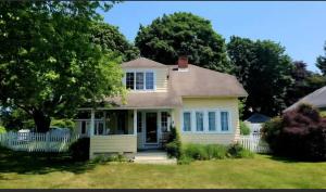 een huis met een wit hek in een tuin bij Enchanted Cottage 1 block to beach in Madison