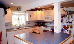 een keuken met witte kasten en een zwart aanrechtblad bij Enchanted Cottage 1 block to beach in Madison