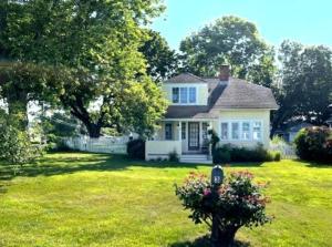 een wit huis in een tuin met een boom bij Enchanted Cottage 1 block to beach in Madison