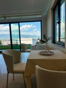 a dining room with a table and chairs and windows at Resident Apartments Nota in Skopje