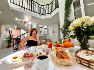 Una donna con un cappello seduta a un tavolo con del cibo di Hotel Bombay a Baños
