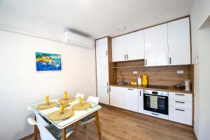 a kitchen with white cabinets and a table with chairs at Platanus City Center in Trebinje