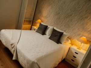 a bedroom with a large white bed with two lamps at Casa El Refugio in Monforte de Lemos