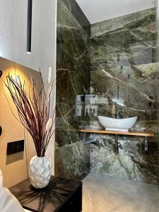 ein Badezimmer mit Waschbecken und einer Vase auf einem Tisch in der Unterkunft Umberto 28 Guest House in Sassari