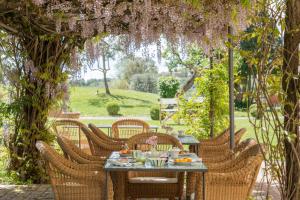 an outdoor dining table with wicker chairs under an arch with flowers at Hotel Certosa Di Maggiano in Siena