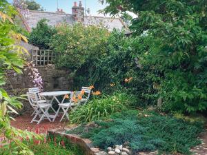 einen Garten mit einem Tisch, Stühlen und Blumen in der Unterkunft Smithy Cottage in Keldhead