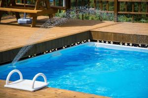 Ein Swimmingpool mit einem weißen Stuhl neben einer Holzterrasse in der Unterkunft Domki Redda in Kopań