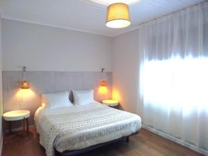 ein Schlafzimmer mit einem Bett mit zwei Tischen und einem Fenster in der Unterkunft Casa de São Roque Açores in Ponta Delgada