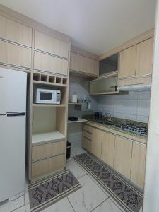 a kitchen with a refrigerator and a microwave at Confortável Apto de 2 Quartos - Lagoa Quente in Caldas Novas