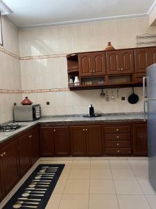 een keuken met houten kasten en een koelkast bij Al houceima in Al Hoceïma