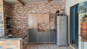 uma cozinha com uma geladeira e uma parede de tijolos em Chácara Liberdade em Pirenópolis