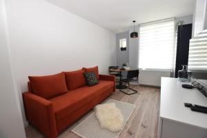 a living room with a red couch and a table at Apartamenty K1 wi-fi netflix gratis ! in Wałbrzych