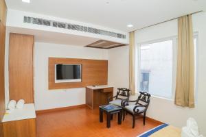 a living room with two chairs and a tv at Grand Hridey 1 minute from Railway Station in Amritsar