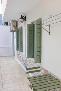 a row of green shutters on a building with stairs at Terra Olivae Syros in Ermoupoli