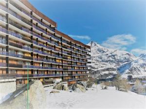 duży budynek w śniegu z górą w obiekcie Résidence Le Bec Rouge - Appartement de charme 3 pièces 8 personnes à Tignes ski aux pieds et proche des commerces dans le quartier du Lac MAE-1993 w mieście Tignes