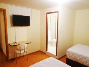 Una habitación de hotel con una cama, un escritorio y un espejo. en Hotel Blue Zafiro, en Bogotá