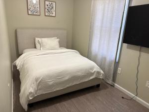 a bedroom with a bed with white sheets and a window at Urban beautiful home Jersey City 15 mins from NYC 15 mins from Newark airport in Jersey City