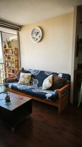 a couch in a living room with a clock on the wall at departamento 2 dormitorios 2 baños full amoblado cercano a aeropuerto in Santiago
