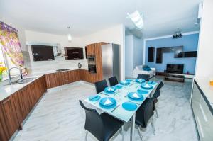 a dining room with a table with chairs and a kitchen at The Waves holiday apartment in Marsaxlokk