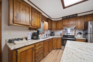 a kitchen with wooden cabinets and granite counter tops at Riverside Mountain Retreat in Boone +24 photos