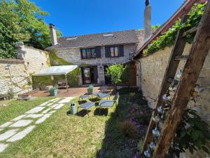 a house with a yard with chairs and a umbrella at Maison Floréal Giverny in Giverny
