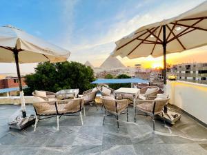 un patio con sedie, tavoli e ombrelloni di Savor The king pyramids hotel a Il Cairo