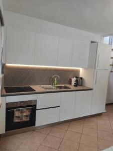 une cuisine avec des armoires blanches, un évier et un réfrigérateur dans l'établissement Casa Carolina, à Montagna in Valtellina 2 autres photos