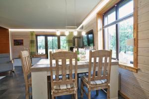 a kitchen with a table with chairs and windows at Modernes Ferienhaus mit Kamin & Garten in ruhiger Lage in Hasselfelde
