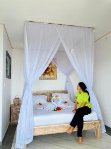 Una mujer sentada en una cama en una habitación. en LAHANGAN SWEET cottages, en Culik