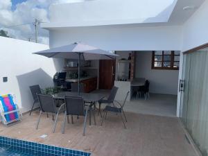 a patio with a table and chairs and an umbrella at Sunset Patacho in Pôrto de Pedras