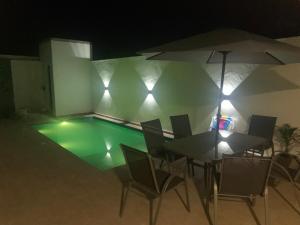 a pool with a table and chairs and an umbrella at Sunset Patacho in Pôrto de Pedras