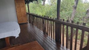 a porch with a bench and a wooden fence at Rhulani Treetop Cottage in Marloth Park