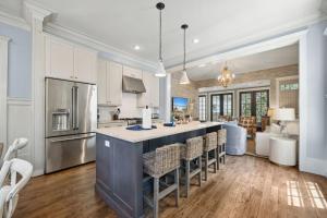 a kitchen with white cabinets and a island with bar chairs at 67 Wiggle Lane - Rosemary Beach - Steps to Tennis Courts, Beach, Pools! in Rosemary Beach